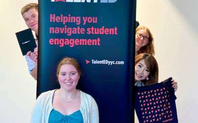 The TalentED YYC Intern standing in front of the company banner, with three team mates behind her.